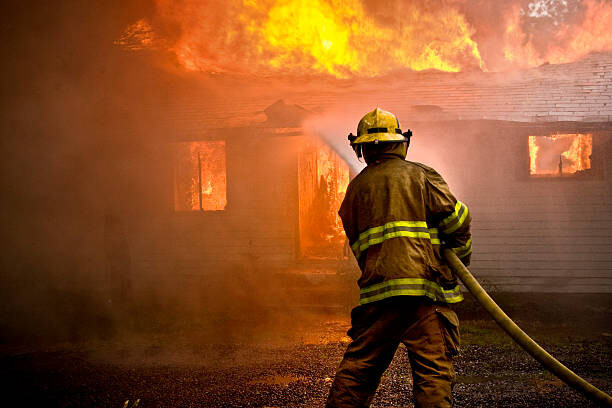 Plakat Firefighter spraying water at a house fire