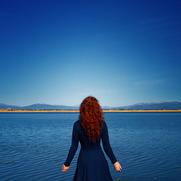 Plakat Redhead in blue dress faces rippled lake