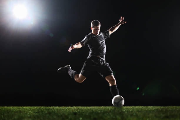 Plakat Soccer player kicking ball on grass,
