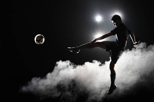 Plakat Soccer player kicking the ball at night on stadium