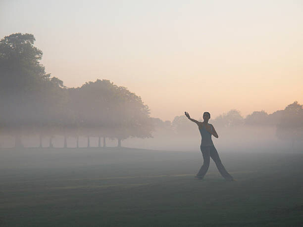 Plakat Woman practicing yoga in foggy field