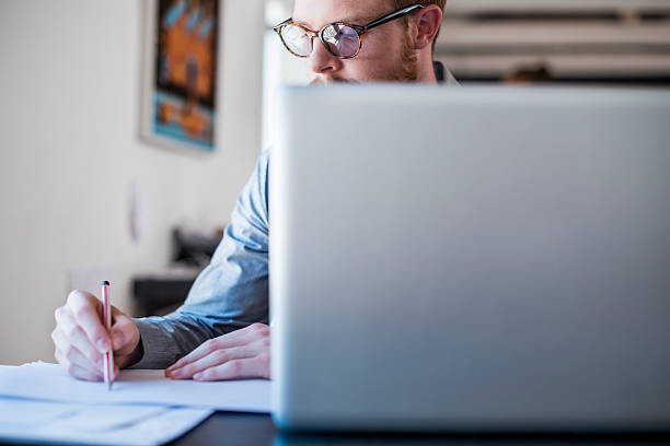 Plakát Businessman writing notes at laptop desk