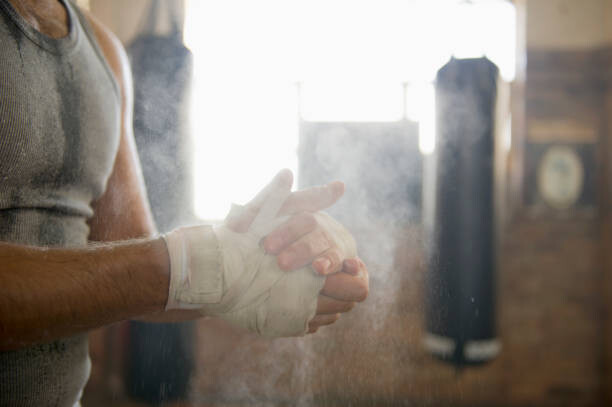 Plakát Caucasian boxer chalking hands in gymnasium
