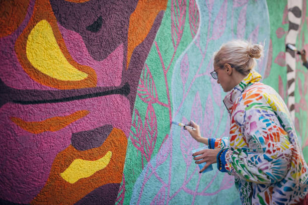 Plakát Female artist painting on wall
