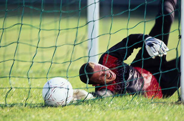 Plakát Male football goalie lying on field,