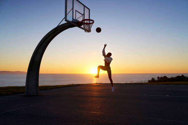 Plakát Mid adult woman playing basketball at sunset