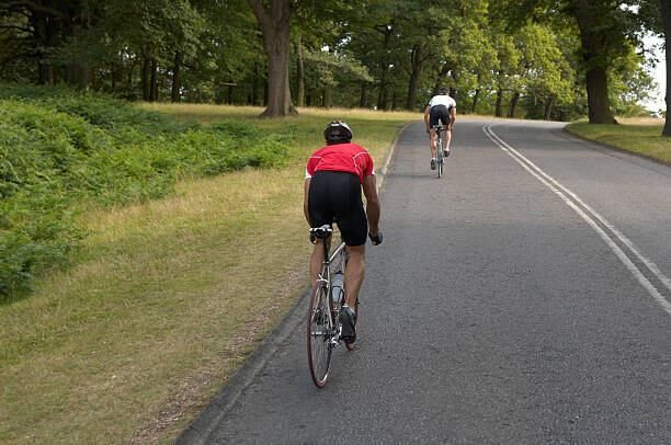 Plakát Two male cyclists on road, rear view