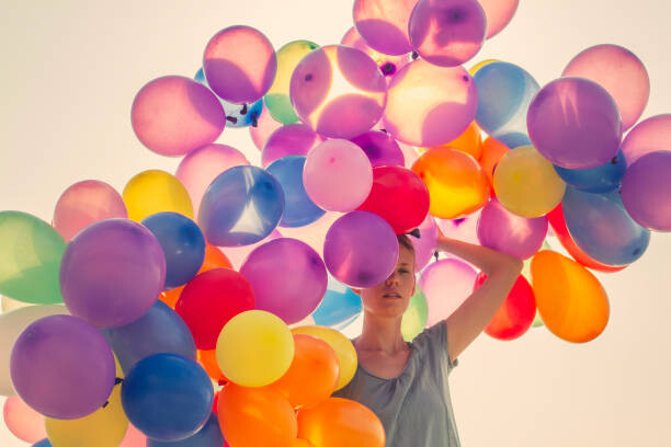 Plakát Young woman walking with many balloons