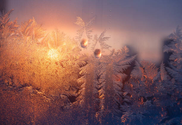 Obraz na płótnie Frosty window with drops and ice pattern at sunset