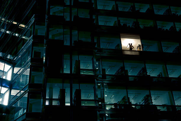 Obraz na płótnie Office building at night, man standing