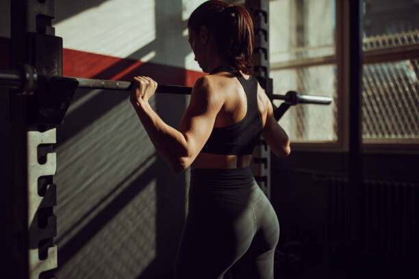 Poster Fit young woman training alone in dark gym