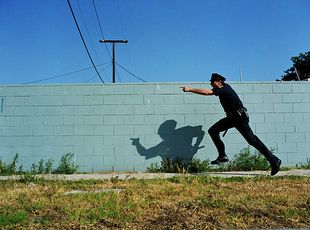 Poster Policeman running next to cement wall,