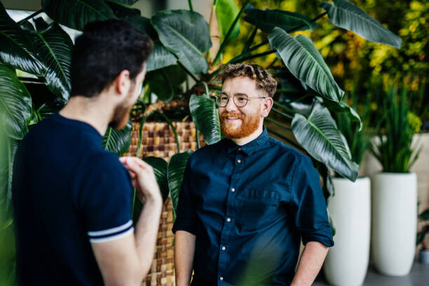 Poster Two Colleagues Standing Amongst Potted Plants