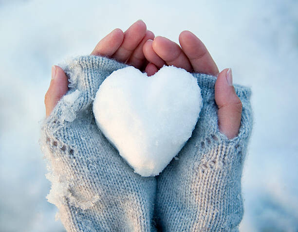 Poster Woman holding heart-shaped snowball, close-up of
