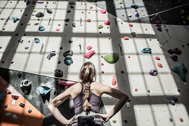 Poster Athlete examining rock wall in gym