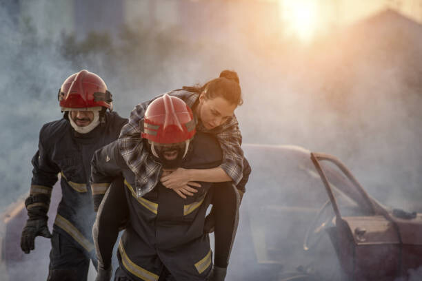 Tablou pe pânză Firefighters rescue a woman, carrying her