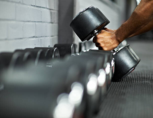Tableau sur toile Athletic Male Picking Up Dumbbells in Gym